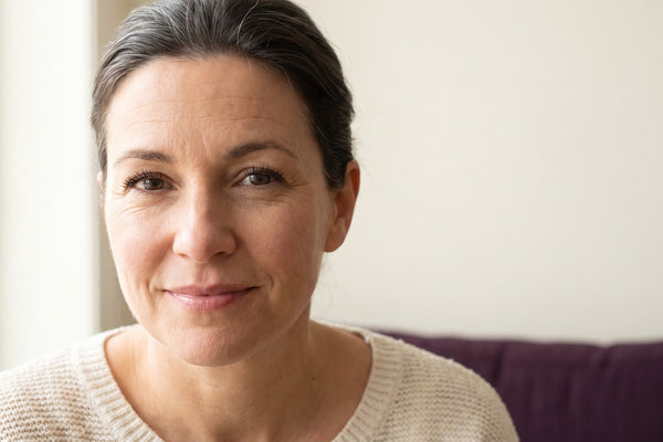Femme québécoise d'une cinquantaine d'années au regard réveillé et lumineux, cheveux gris assumés, beauté après 40 ans