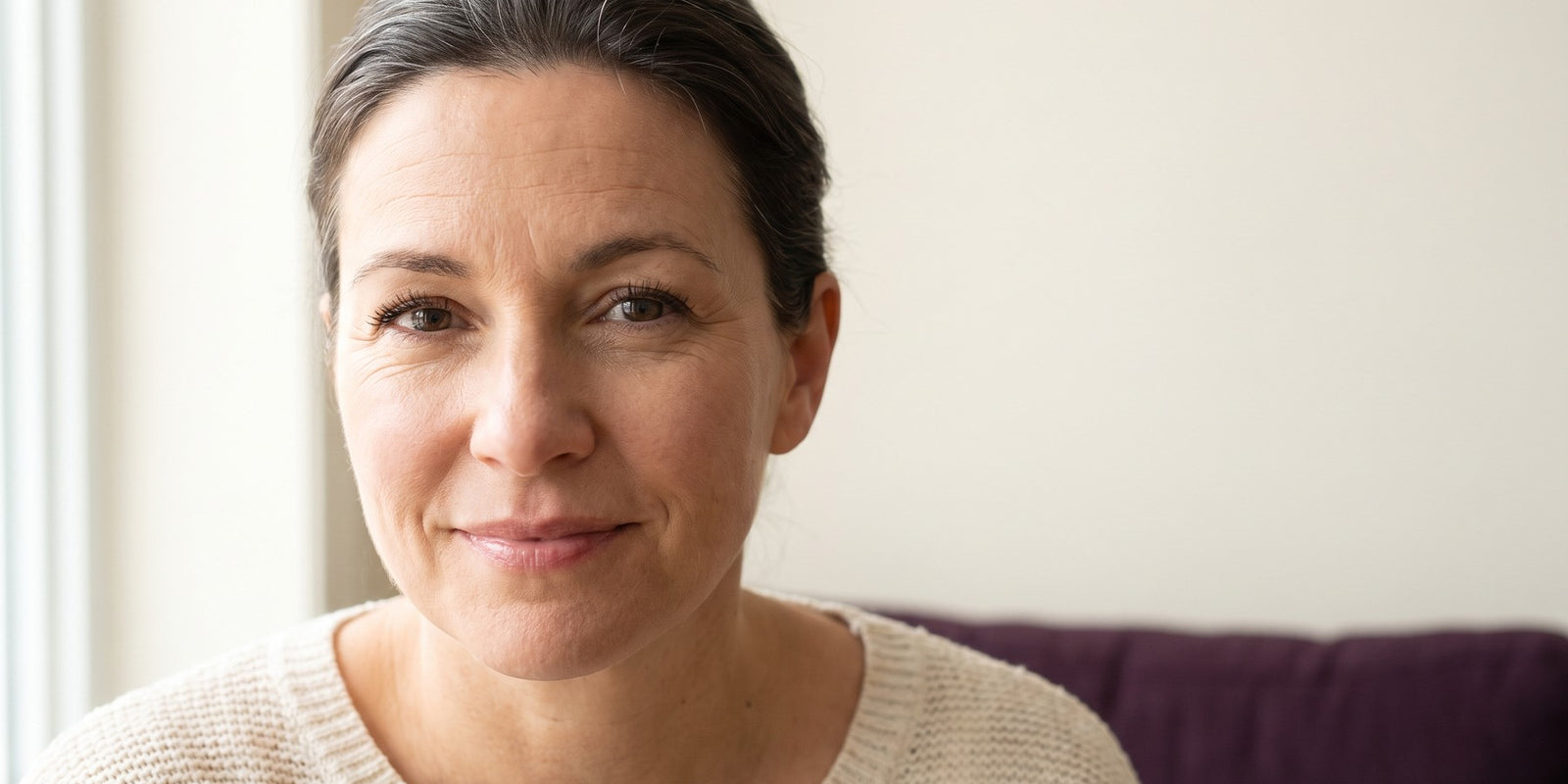 Femme québécoise d'une cinquantaine d'années au regard réveillé et lumineux, cheveux gris assumés, beauté après 40 ans