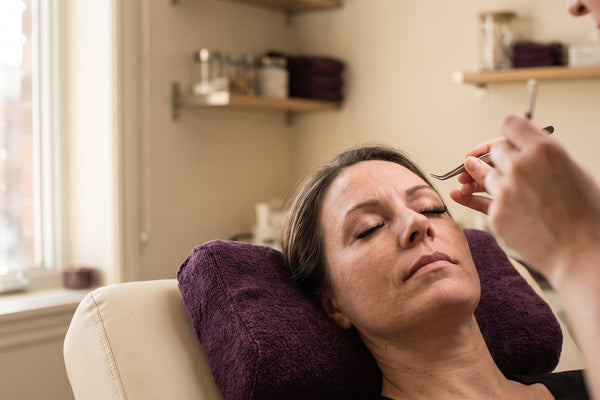 Femme dans une chaise de salon d'extensions de cils, illustrant le temps et le coût récurrents