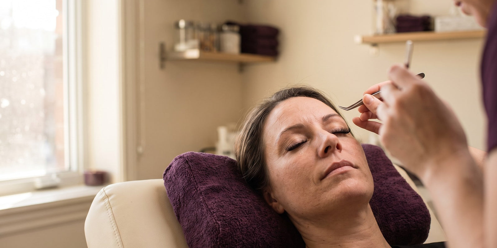 Femme dans une chaise de salon d'extensions de cils, illustrant le temps et le coût récurrents