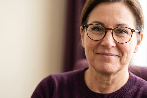 Femme québécoise d’une cinquantaine d’années souriante portant des lunettes fines, avec de beaux cils visibles derrière les verres