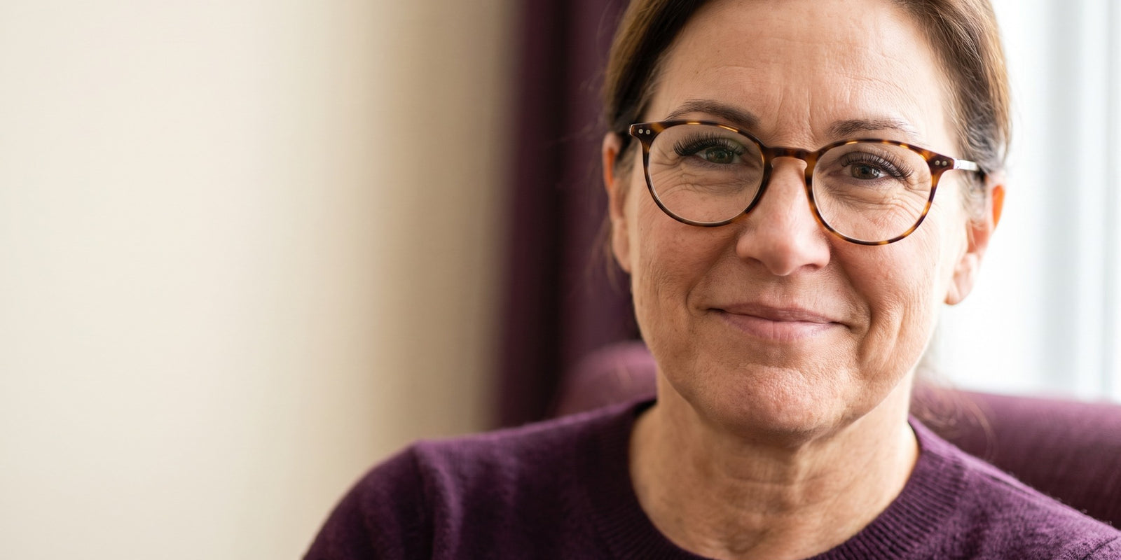 Femme québécoise d’une cinquantaine d’années souriante portant des lunettes fines, avec de beaux cils visibles derrière les verres
