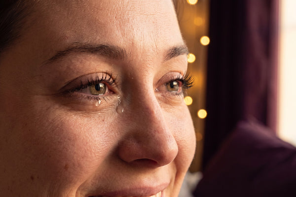 Gros plan émotionnel sur les yeux d'une mariée, une larme sur des cils intacts, lumière dorée