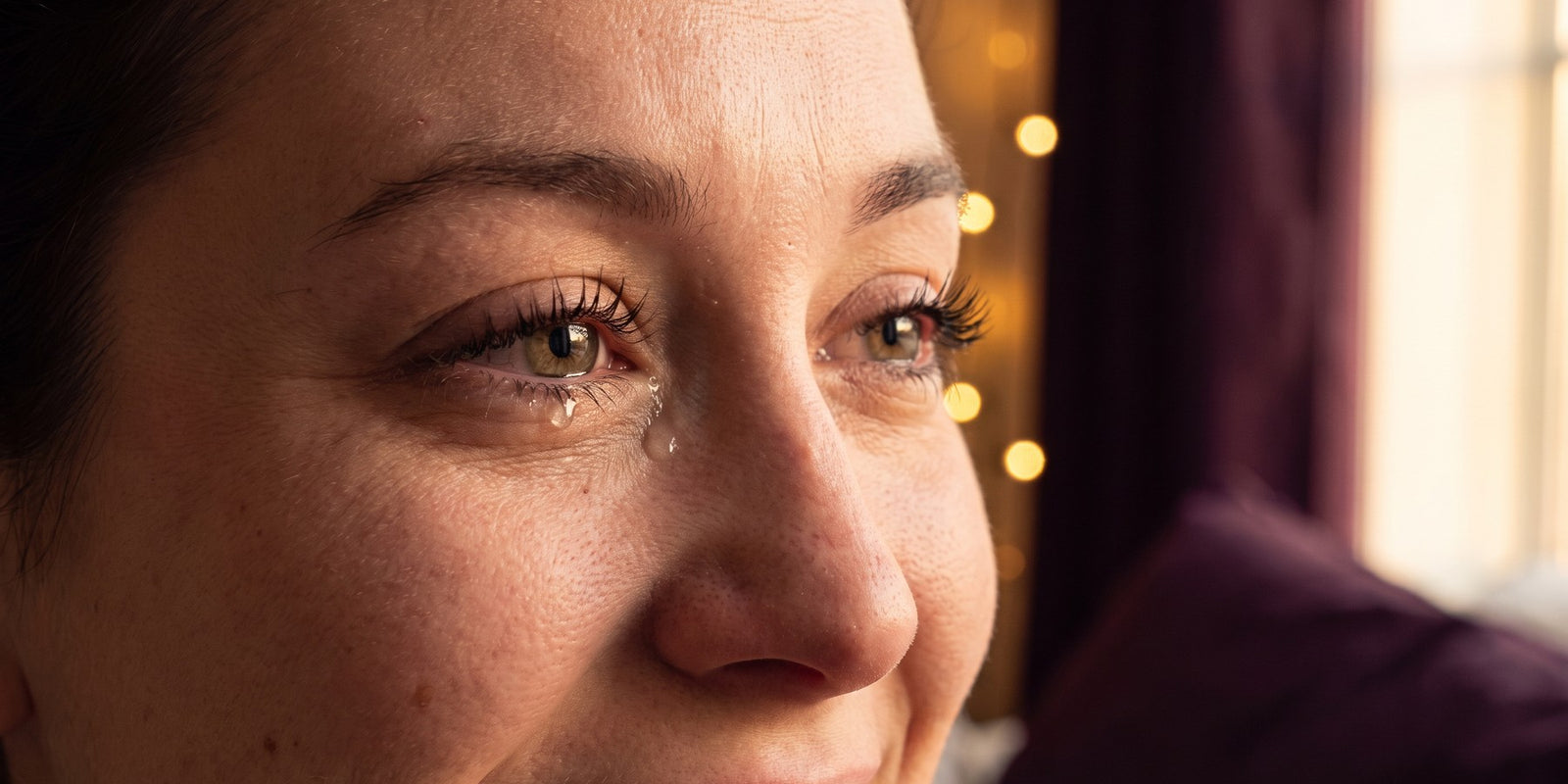 Gros plan émotionnel sur les yeux d'une mariée, une larme sur des cils intacts, lumière dorée