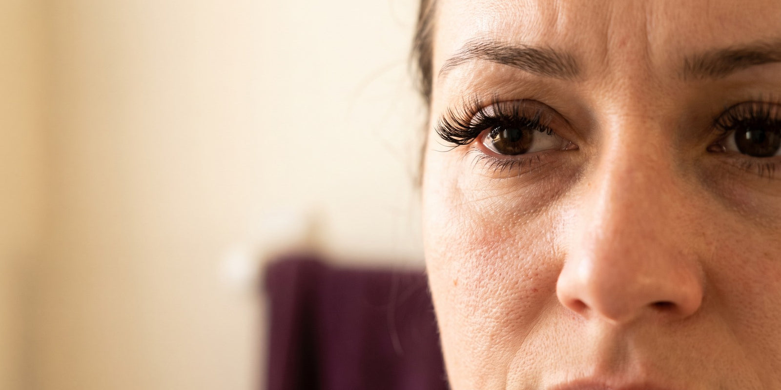 Gros plan sur le coin extérieur d'un œil où une bande de faux cils se soulève légèrement